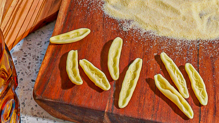 pasta and semolina flour on a reddish brown cutting board